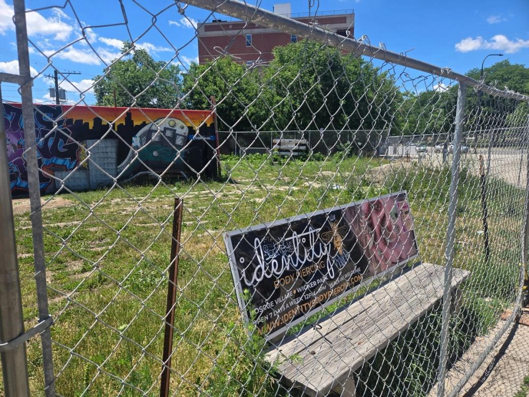 A public bench behind a fence in a grass plot