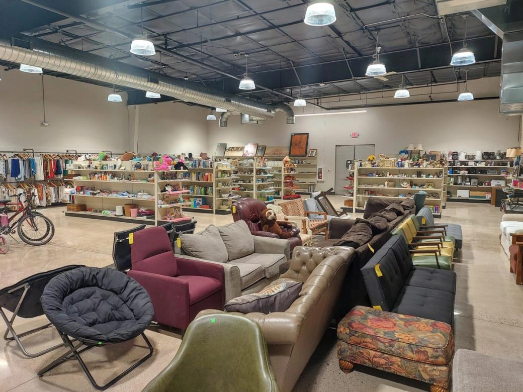 The inside of a thrift store, showing furniture and shelves of household goods.