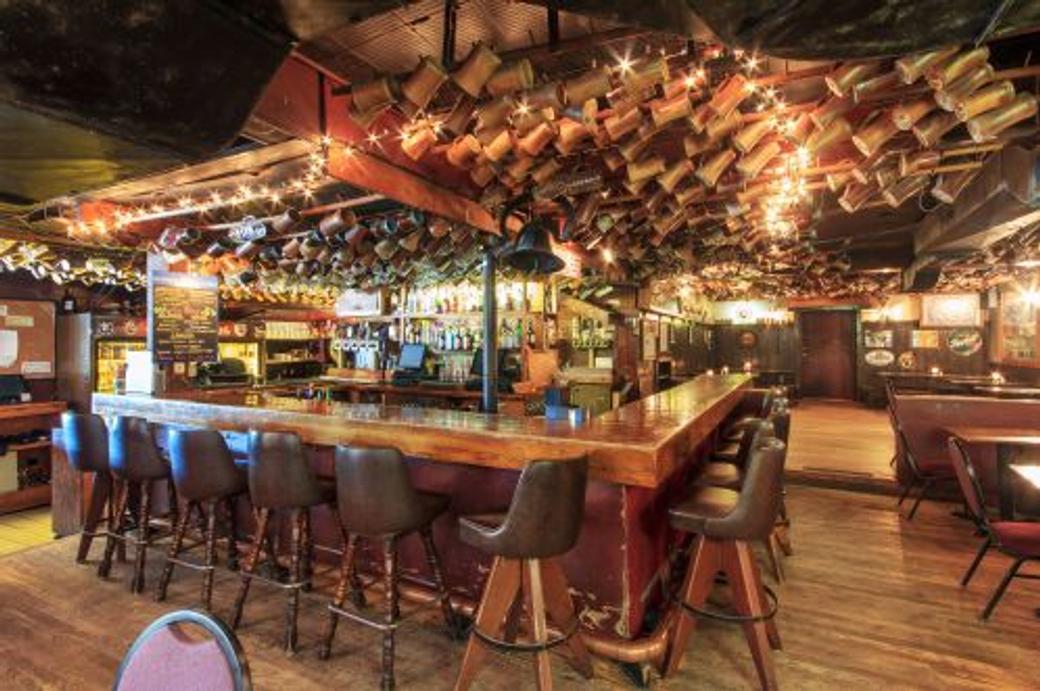 The interior of a bar with steins hanging from the ceiling. 