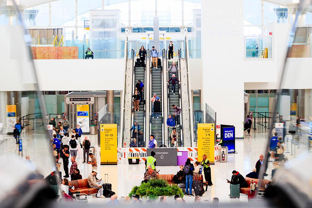 Crowds of travelers move around the main terminal at Denver International Airport.