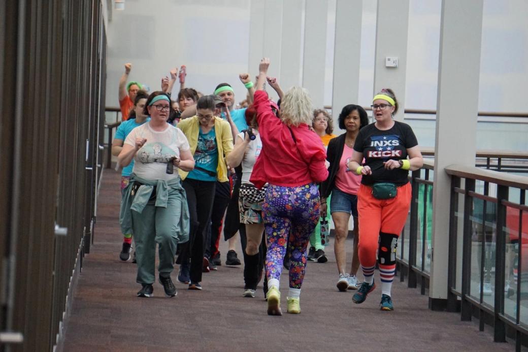 Wearing bright colored pants, a group of people walk through the mall.
