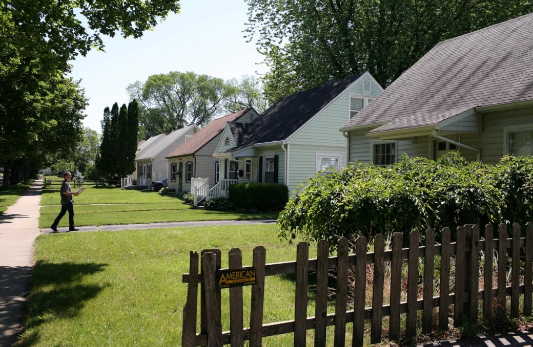 A row of houses with green lawns line a street in Madison.