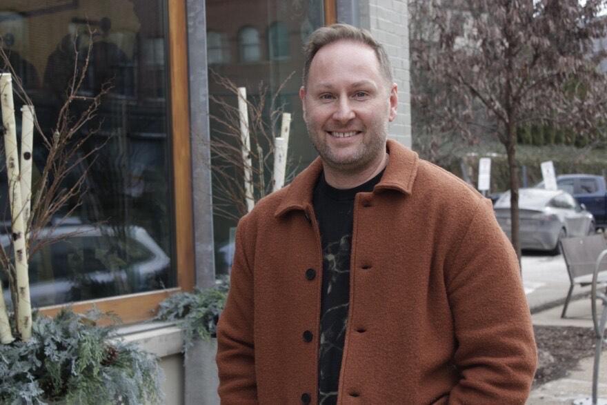 Thomas West, a white man with blonde hair and a rust jacket, standing in front of his store in Lawrenceville