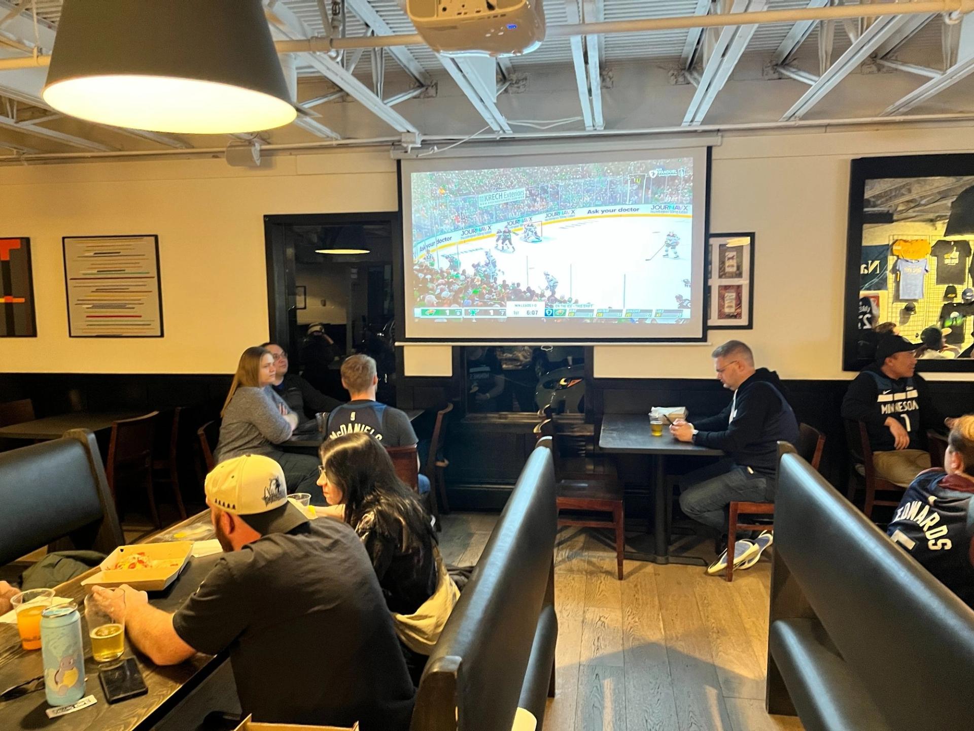 A restaurant with people gathered around a projector