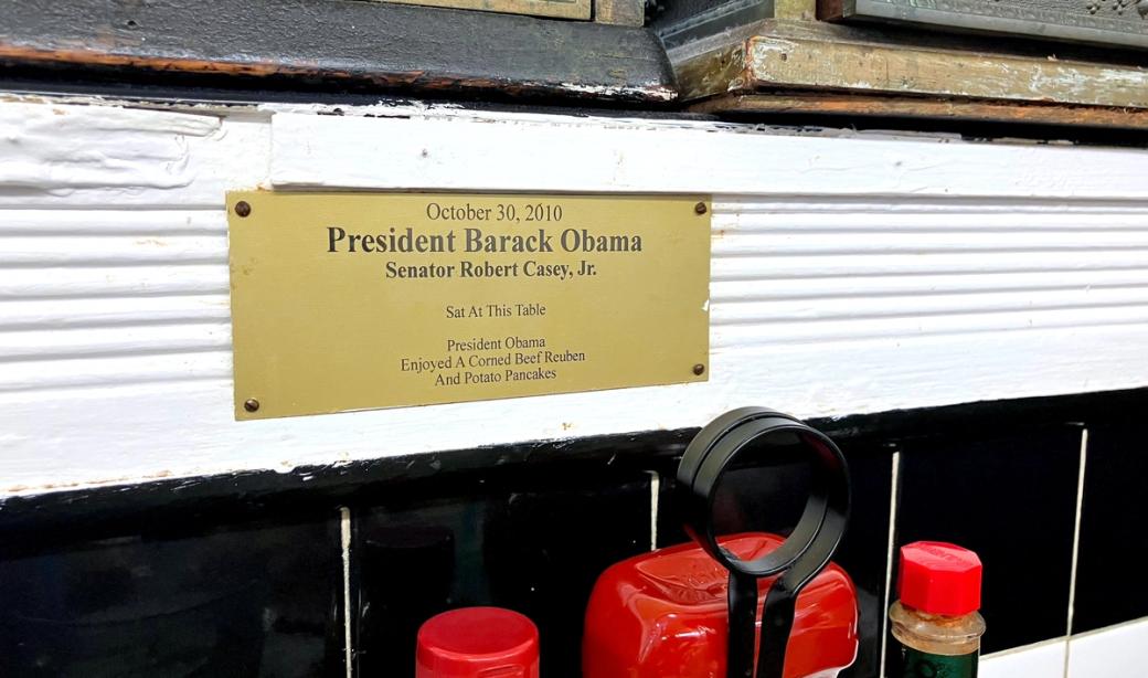 A plaque that reads "October 30, 2010. President Barack Obama. Senator Robert Casey, Jr. Sat At This Table. President Obama enjoyed a corned beef reuben and potato pancakes