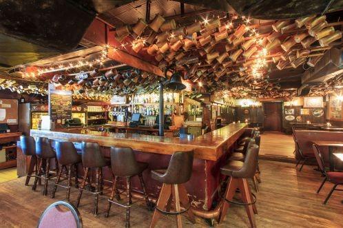 A bar with wooden tables and leather chairs and wood floors.