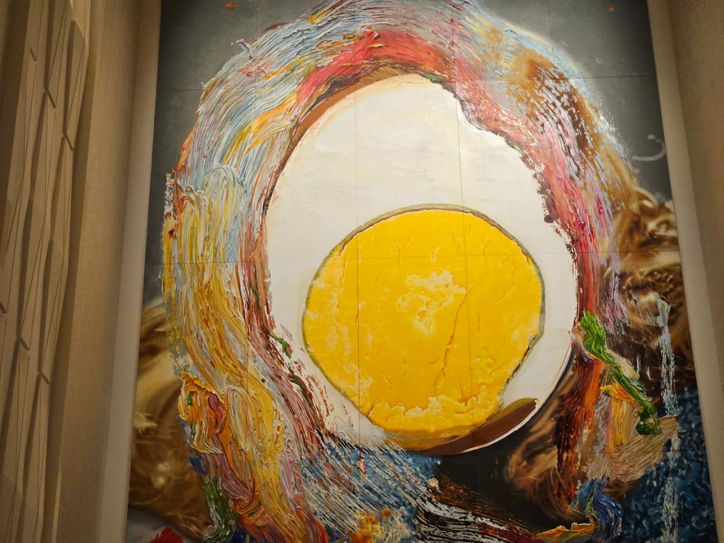 Artwork with a woman's head hidden behind an egg. 