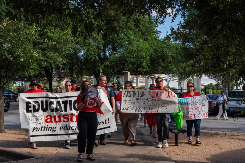 A group of people wearing red and holding white protest signs. 