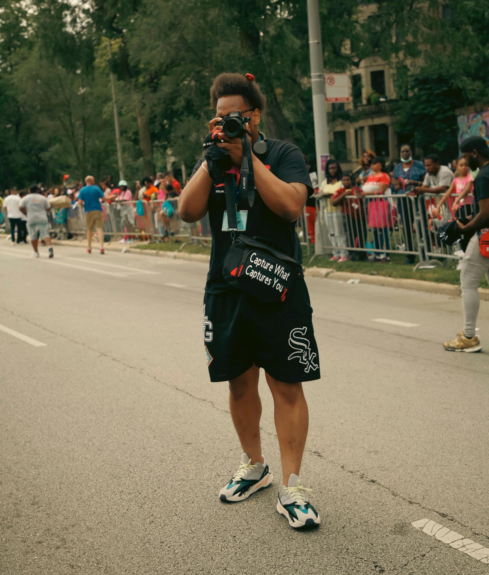 City Cast Chicago podcast host Jacoby Cochran poses with a camera at the Bud Billiken Parade