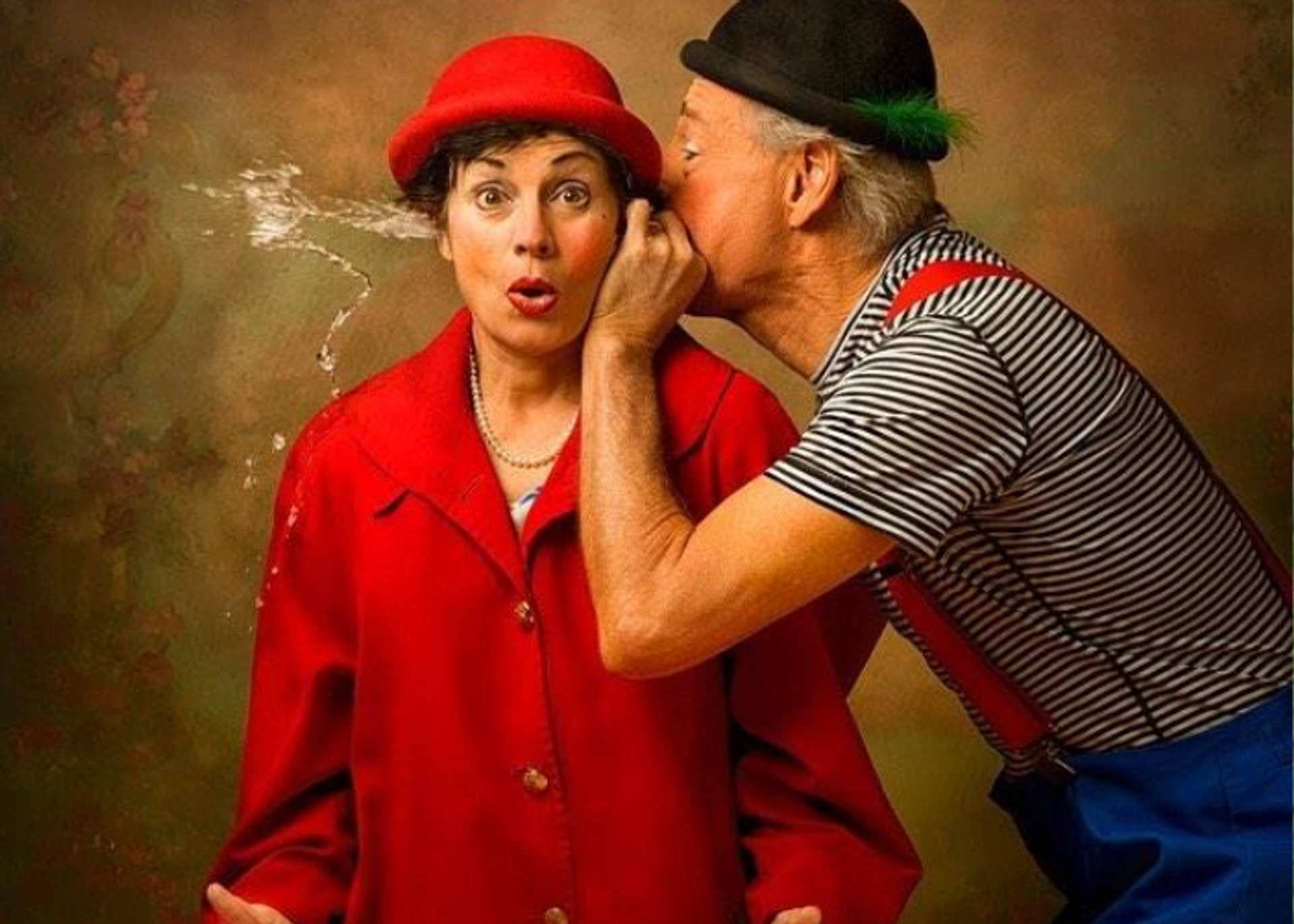 A man seeming to spit water through a woman's ears.