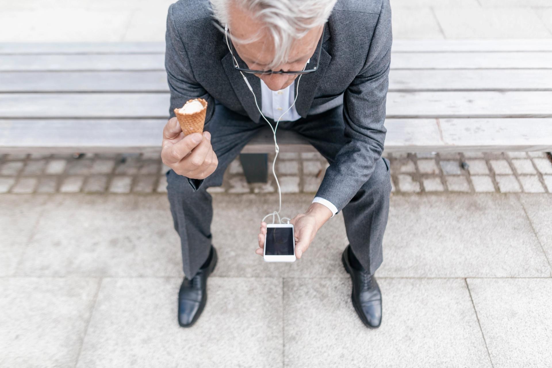 Man eating ice cream cone while listening to podcast