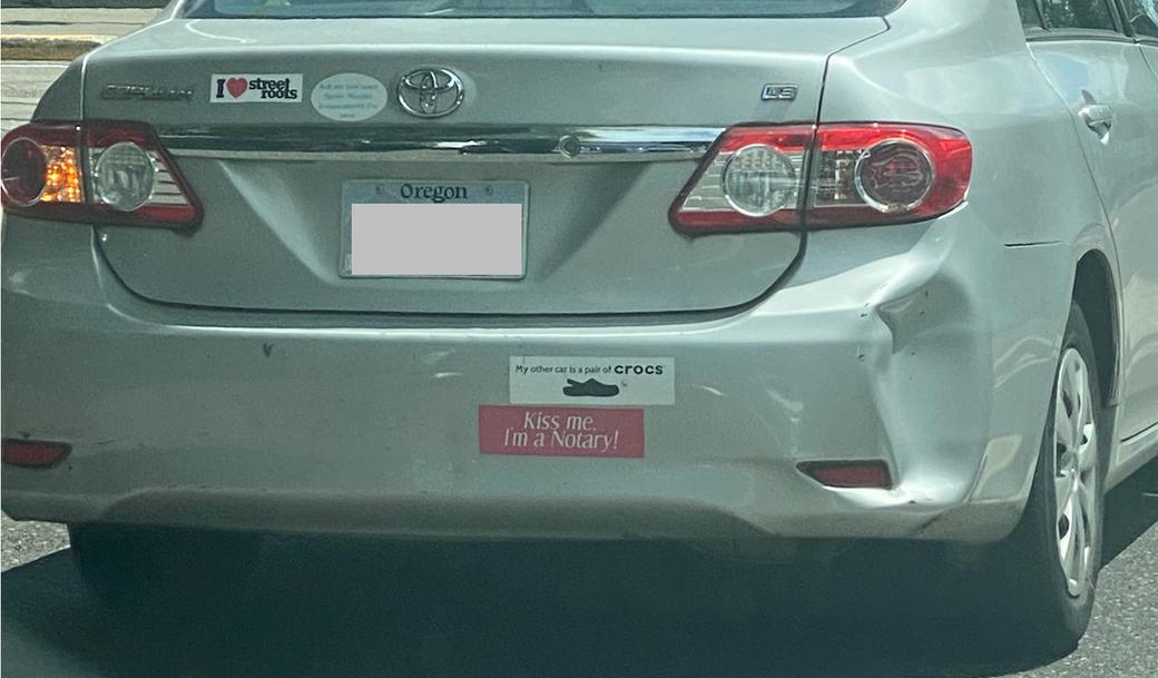 Stickers on this gray Toyota read: “My other car is pair of CROCS,” “Kiss me I’m a Notary,” and “I Heart-Symbol Street Roots”