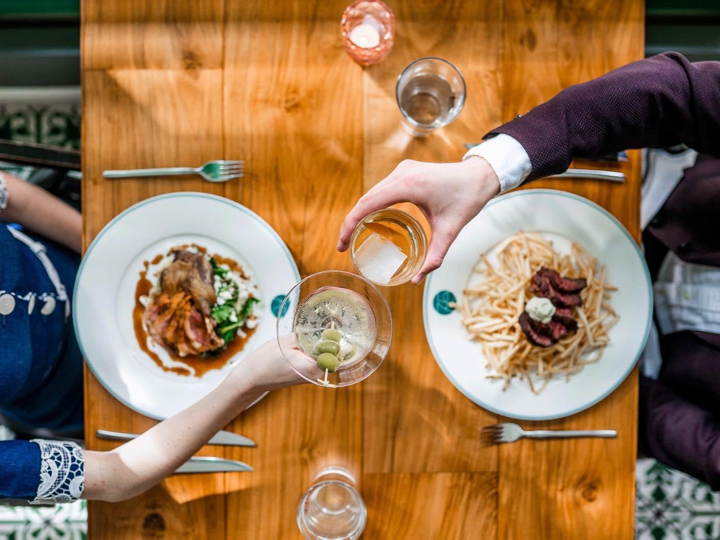 a dining couple cheers over a meal at French 75