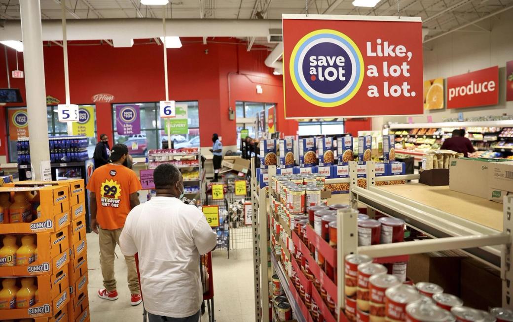 People in a store aisle, there's a sign that says "save a lot. Like, a lot a lot."