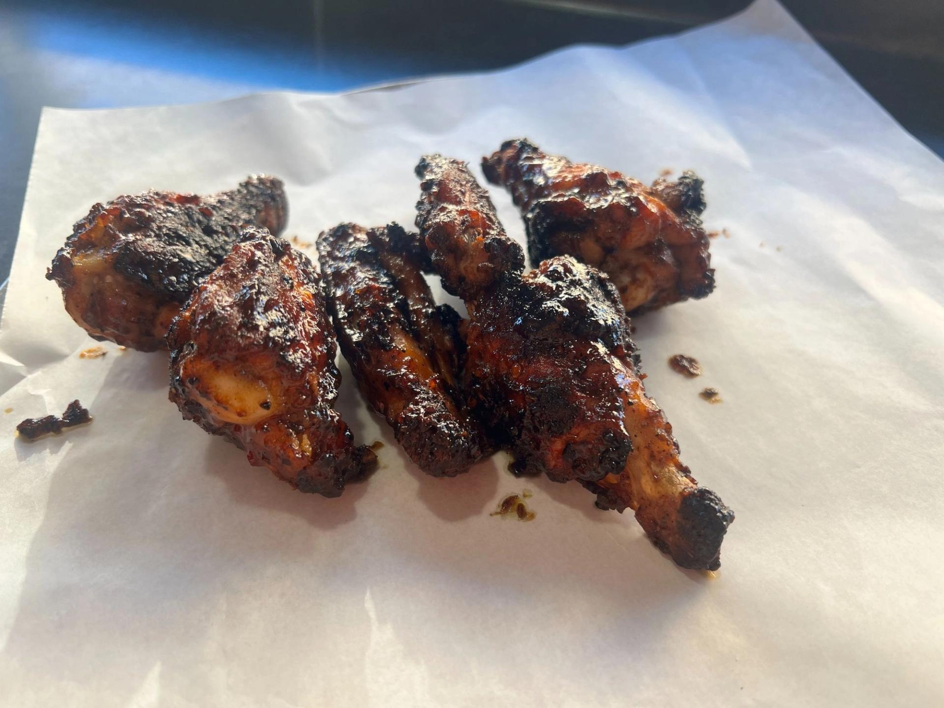 A bundle of charred wings on restaurant paper