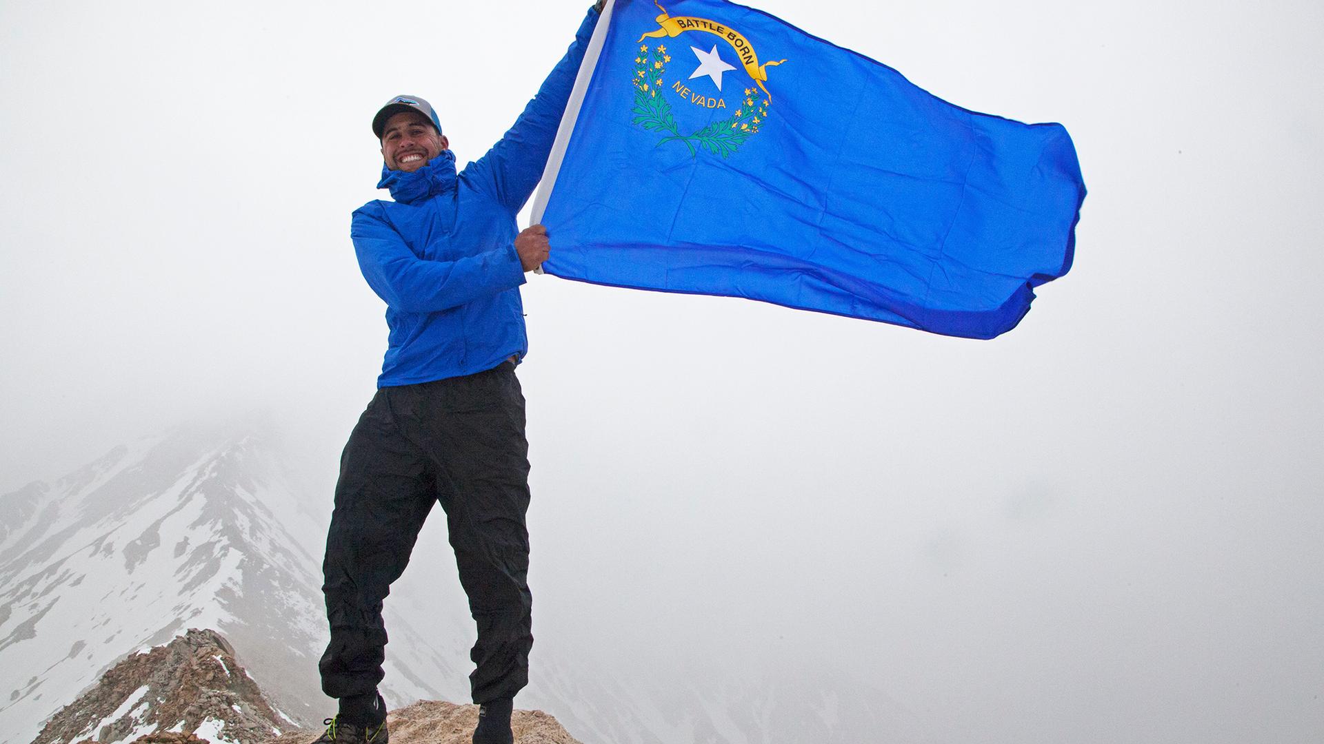 A man waves the Nevada flag at the summit of Boundary Peak.