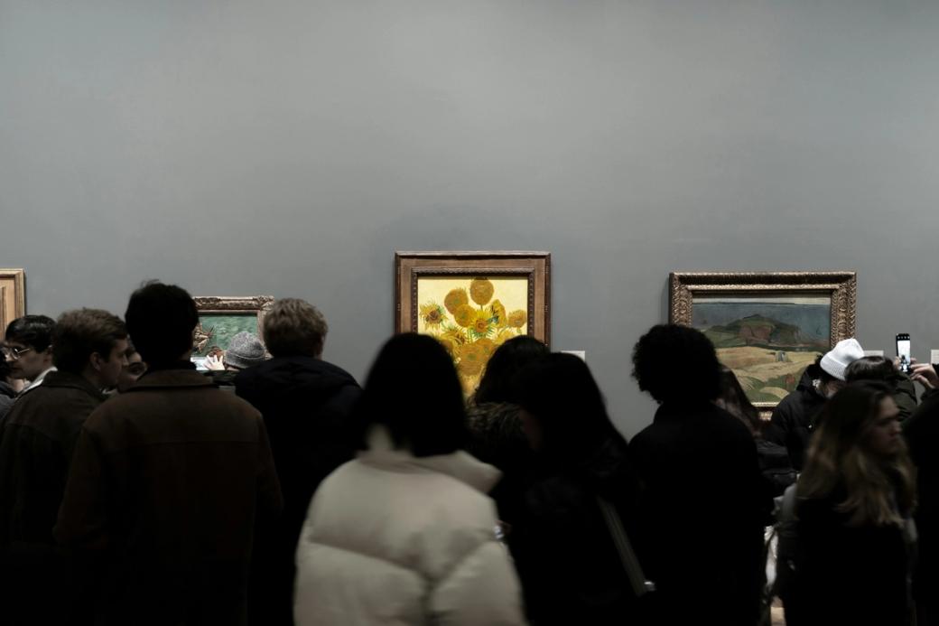 Silhouettes of visitors slightly obscure the frame of van Gogh's "Sunflowers" 