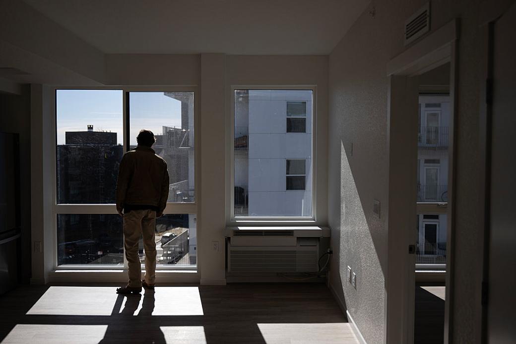 Person looks out of a window in an empty apartment