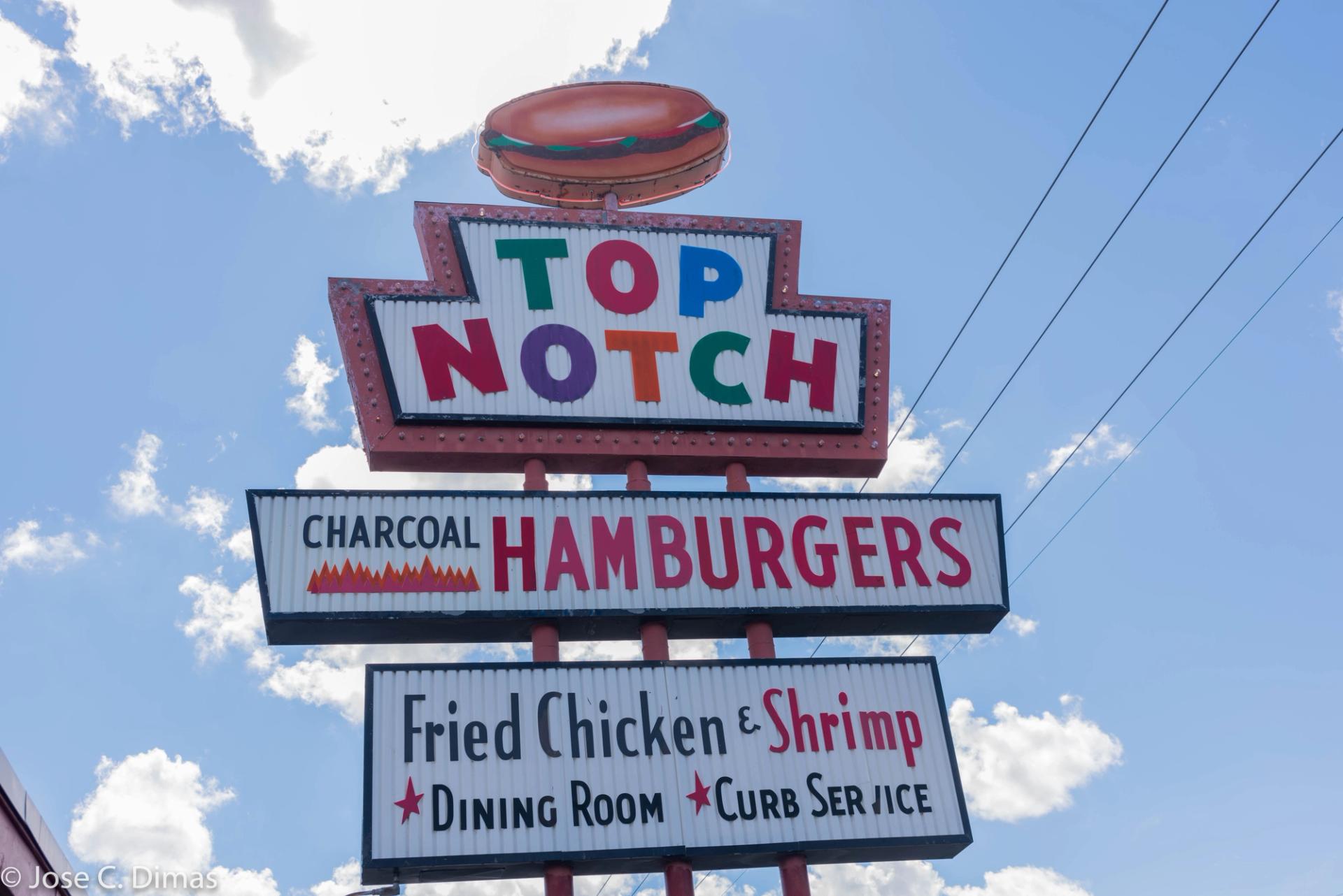 A colorful sign for Top Notch Hamburgers. The sign has a burger on top.