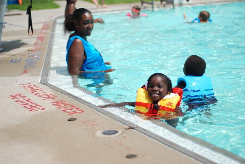 A woman and two children swim in a public pool