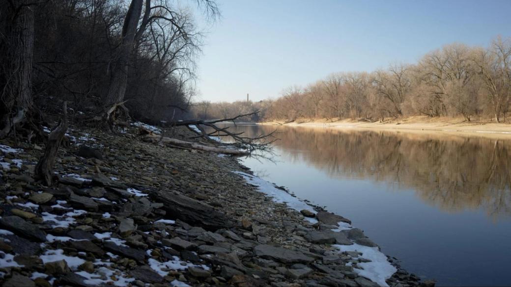 The Mississippi River in winter, with leafless trees in the background and some snow on the shore.