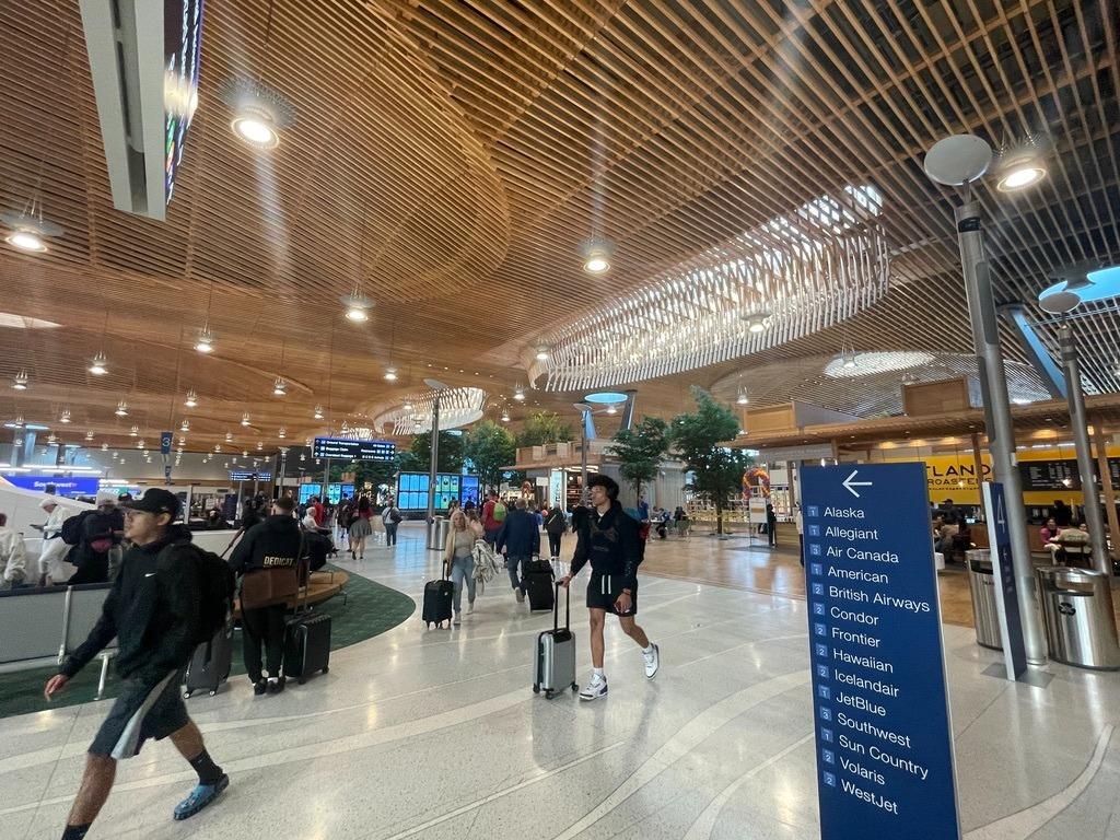 Travelers with suitcases move under the new wood ceiling at PDX