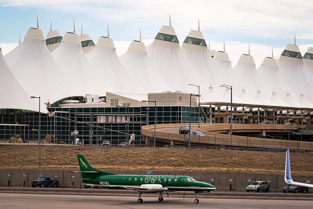 A small green plane with “Key Lime Air” on the side taxis in front of Denver International Airport. 
