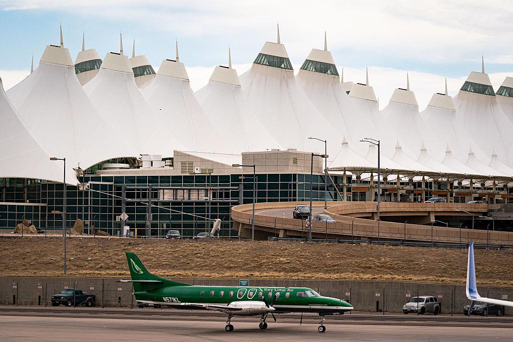 A small green plane with “Key Lime Air” on the side taxis in front of Denver International Airport.