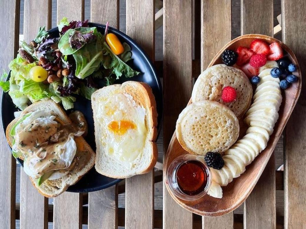 Overhead view of two breakfast plates on a wooden slat table.
