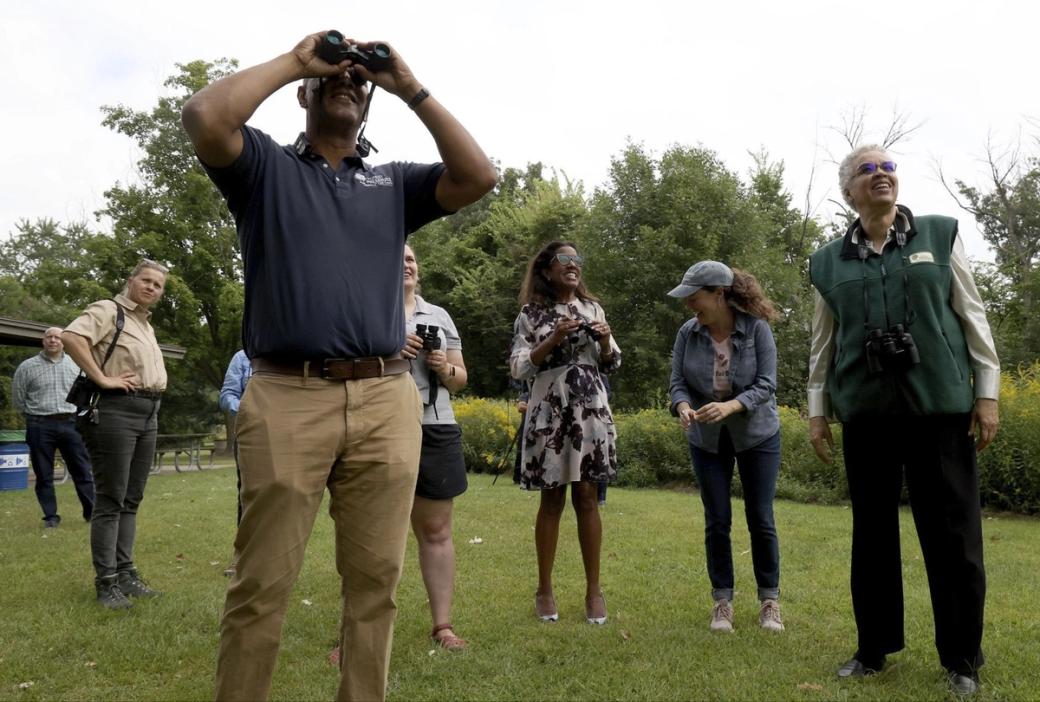 A group of people looking up. One of which is looking with binoculars