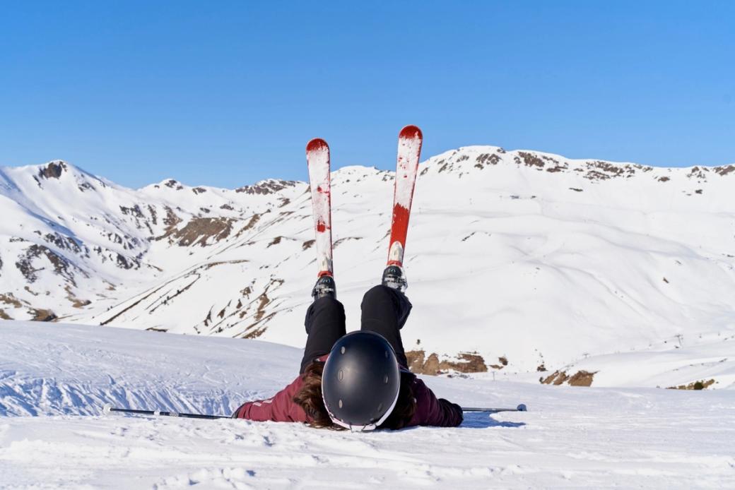 Beginner skier lying on the snow after a fall while skiing