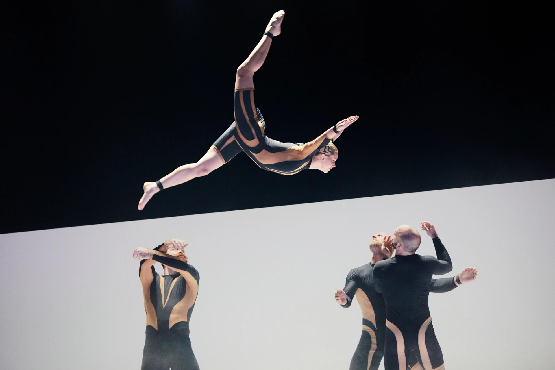 An acrobat soaring over the heads of two other performers.