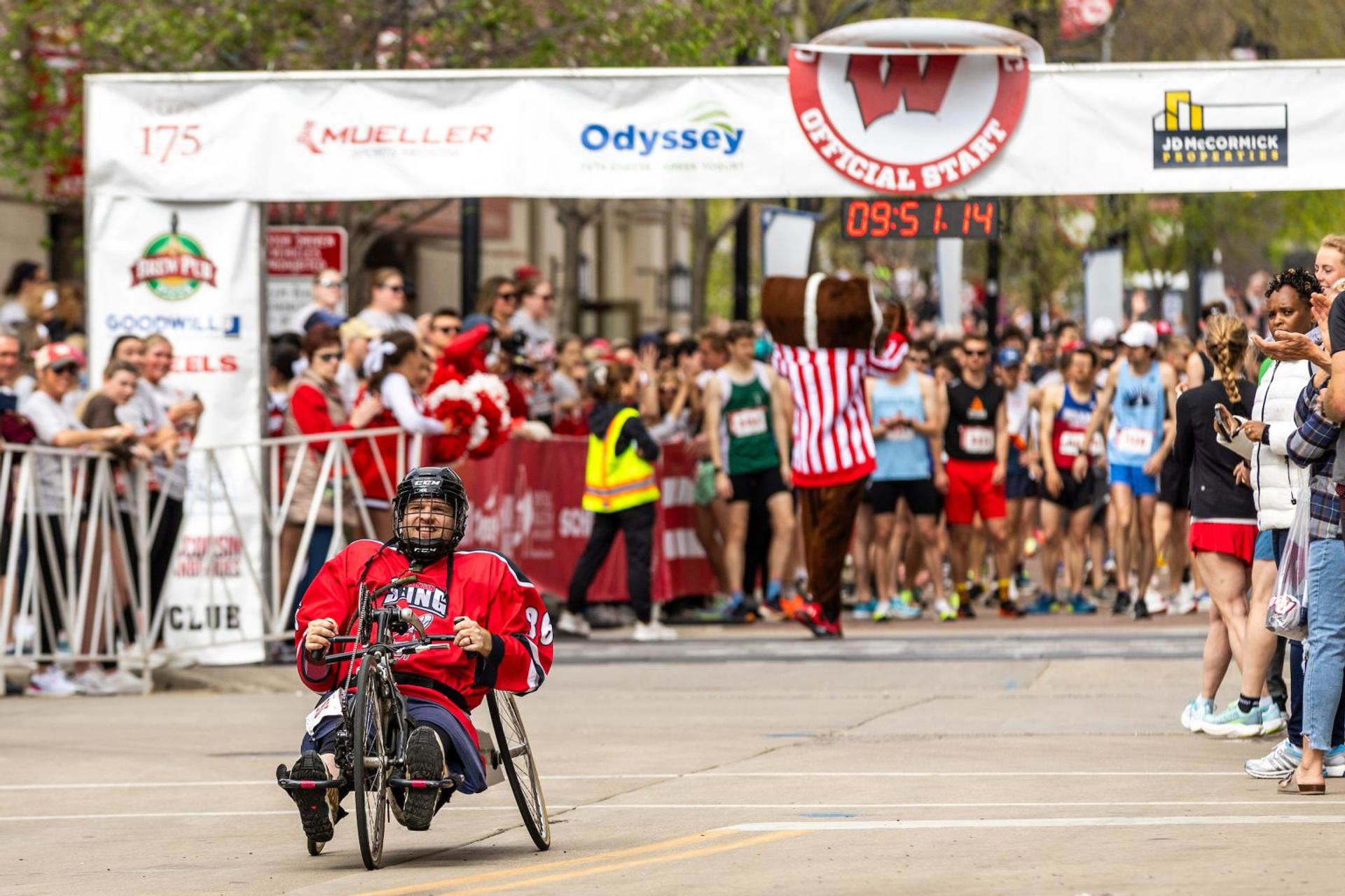 A man in a wheelchair leaving the starting line of a race.
