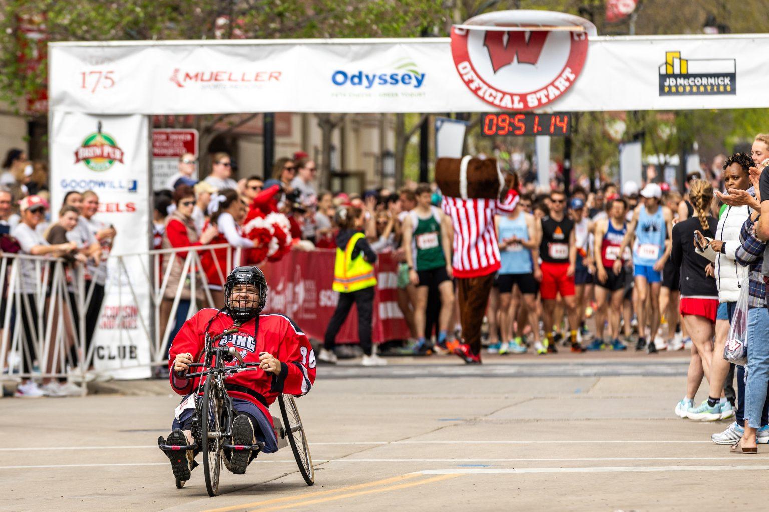 A man in a wheelchair leaving the starting line of a race.