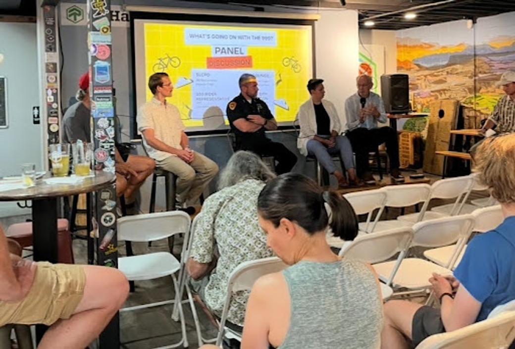 Attendees sit facing a panel discussion about Salt Lake City’s 999 ride, featuring representatives from the city, police department, and cycling community.