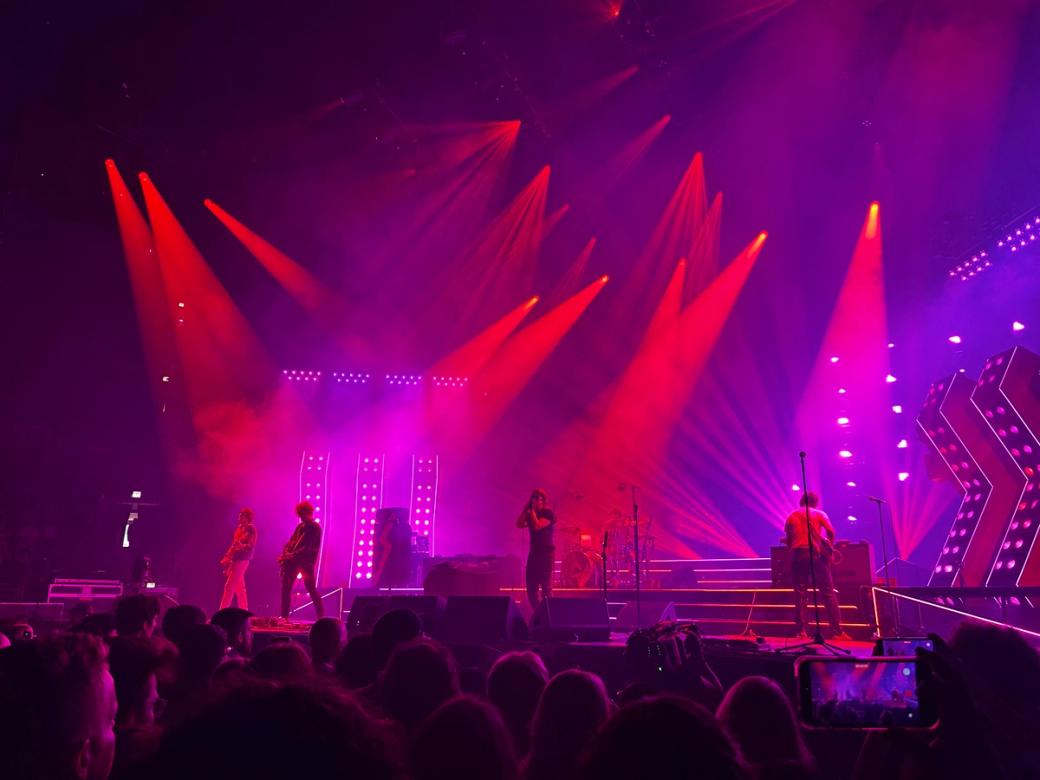 The band The Strokes perform on a Chicago stage with red and purple lights to an audience 