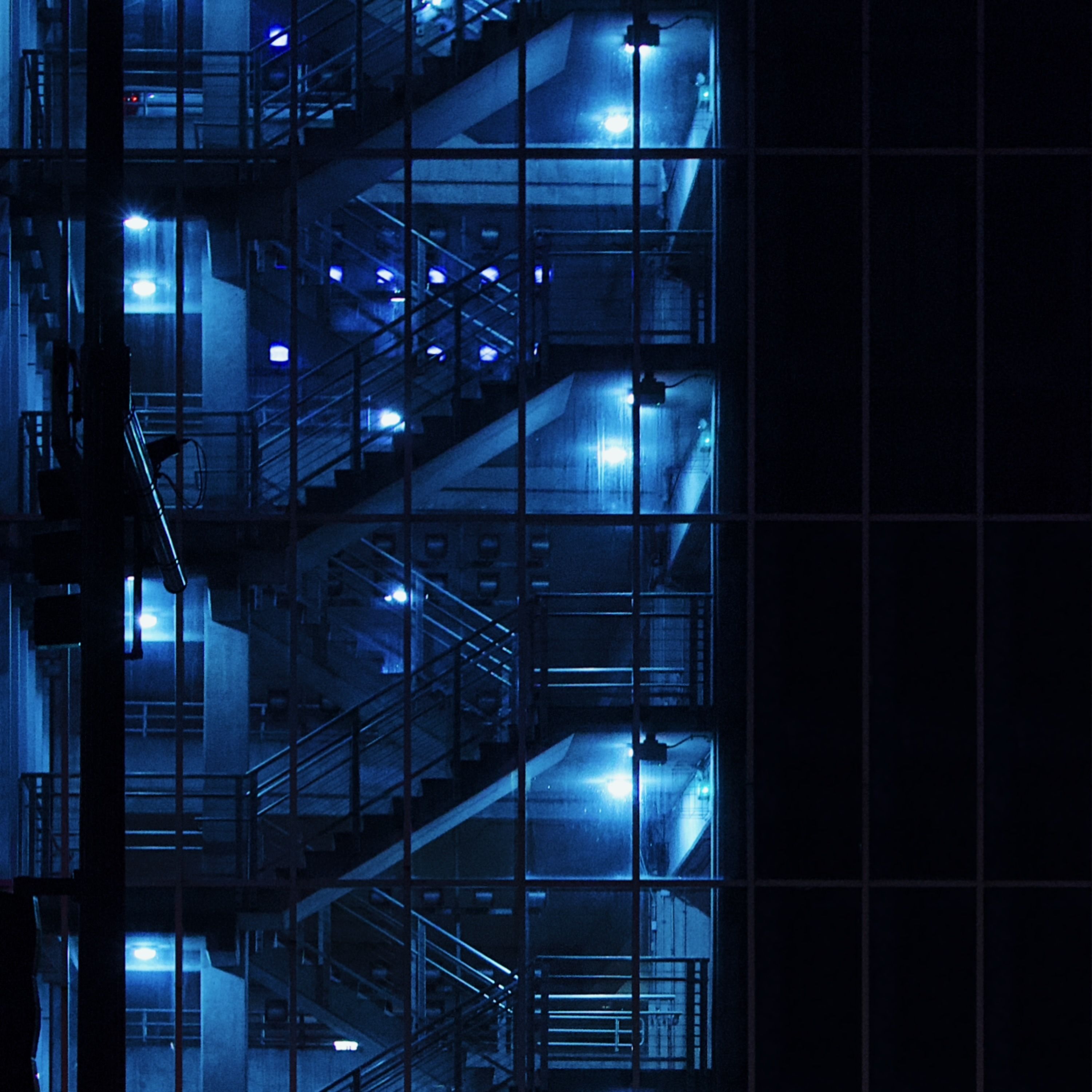 Photo of an industrial staircase bathed in blue light.