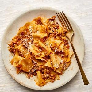 Pappardelle with Ragú Bolognese on a plate with a brass fork