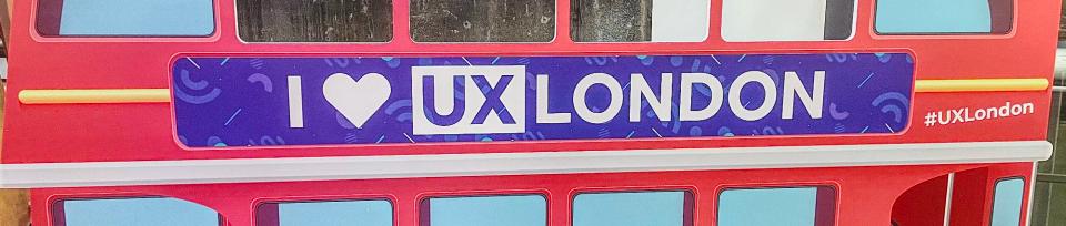 Red London bus cut-out with a sign reading 'I love UX London' and '#UXLondon'.