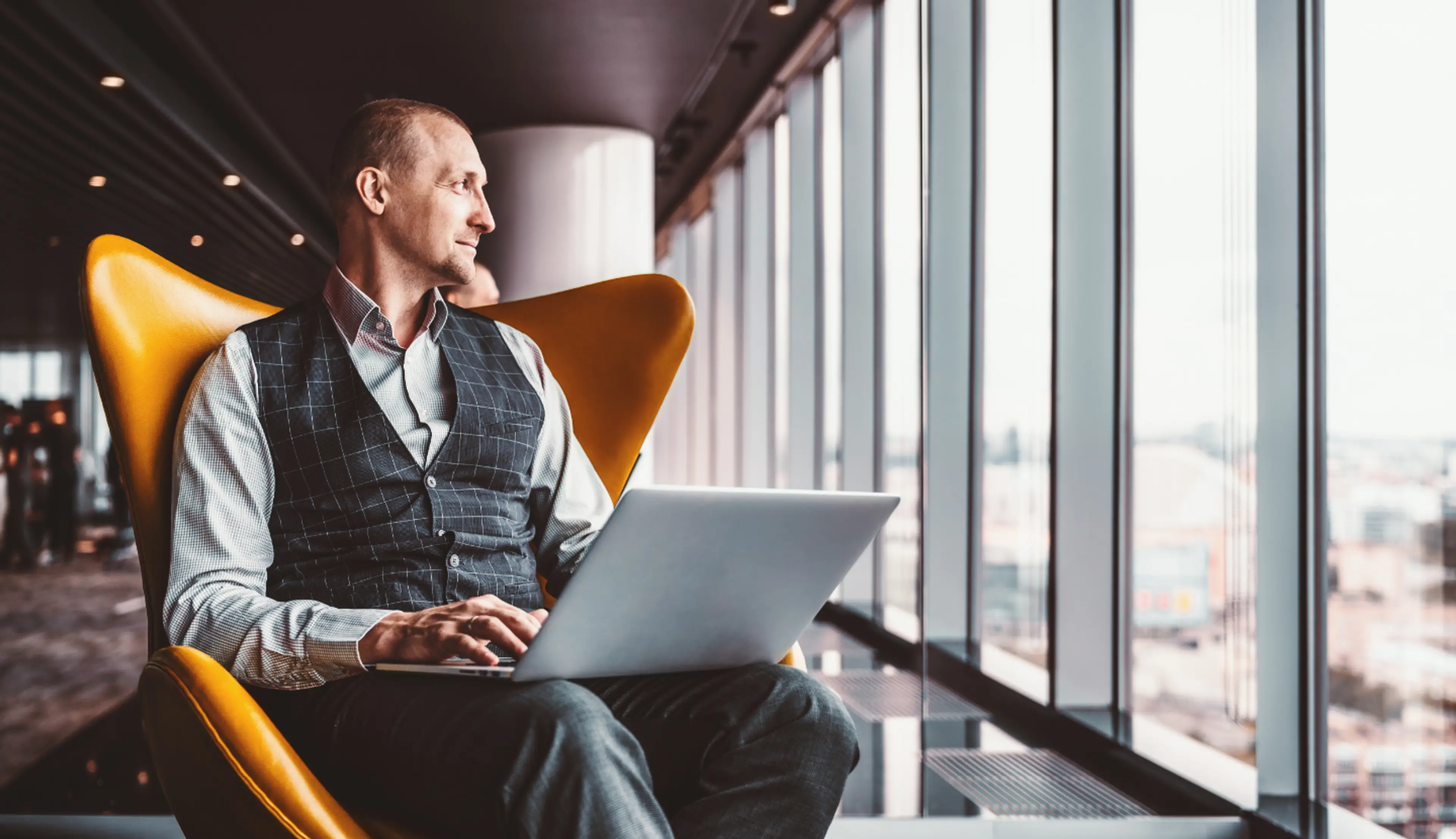 man on laptop looking out window