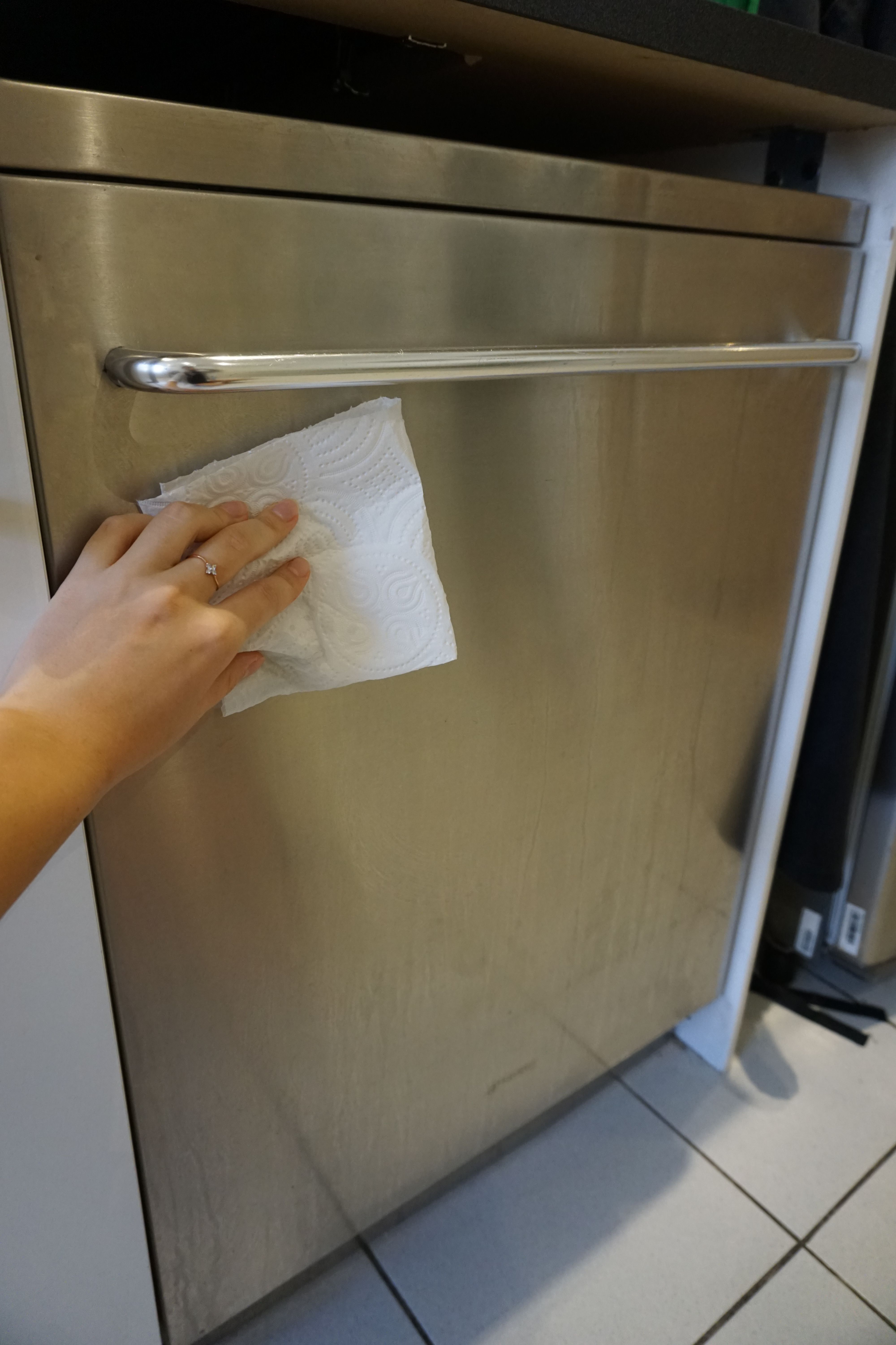 vask utsiden til oppvaskmaskinen En hånd tørker utsiden av oppvaskmaskinen med en klut