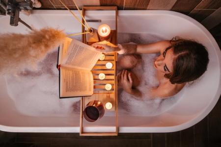 et bilde av en dame som leser en bok i et badekar