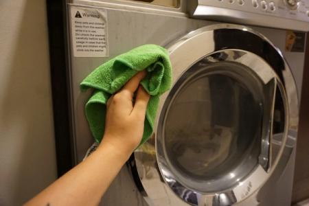 Bildet viser rens av vaskemaskinen med en klut på utsiden, rens vaskemaskin