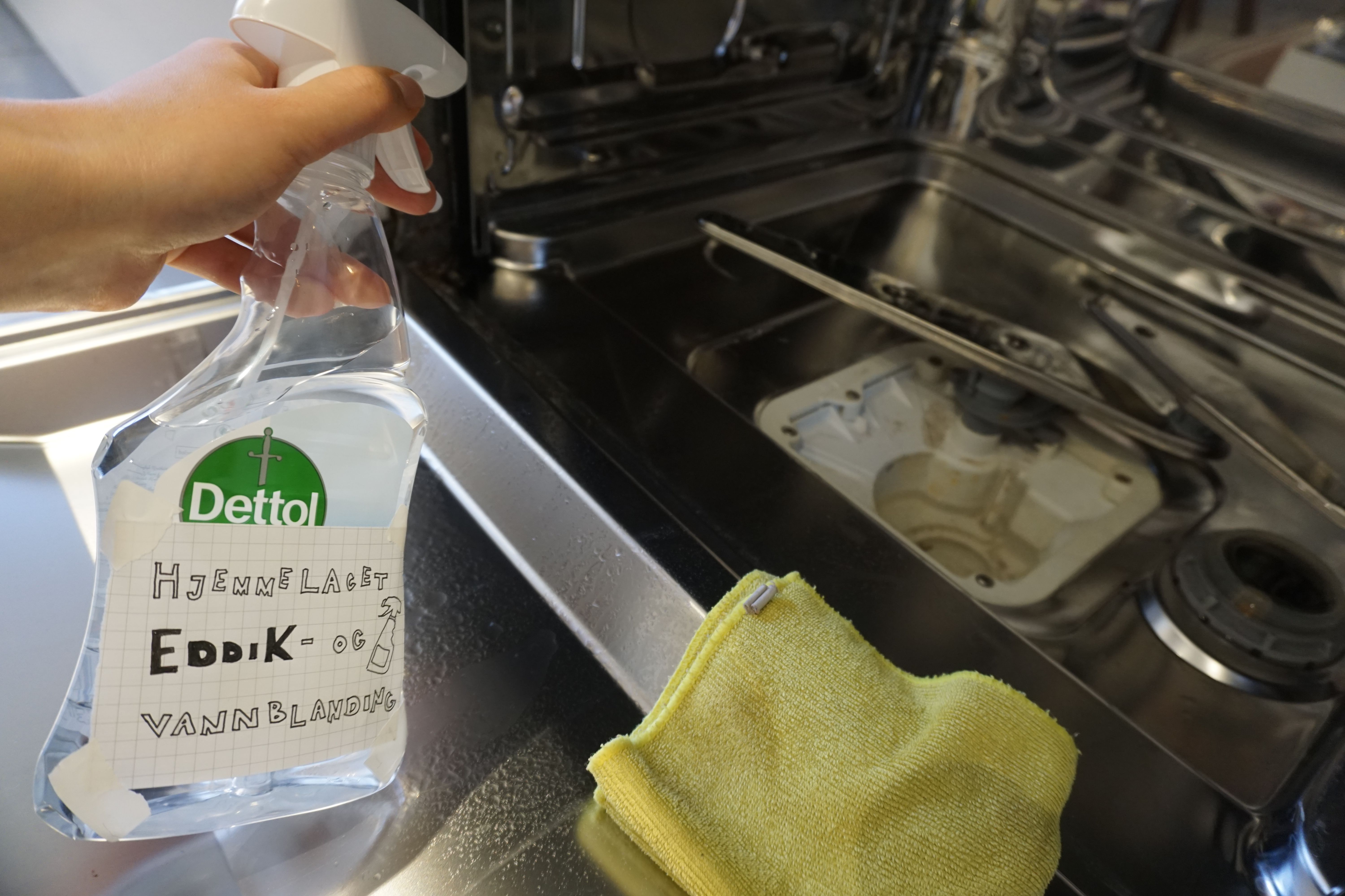 et bilde av en hånd som holder en flaske med en blanding av eddik og vann et bilde av en hånd som holder en flaske med en blanding av eddik og vann