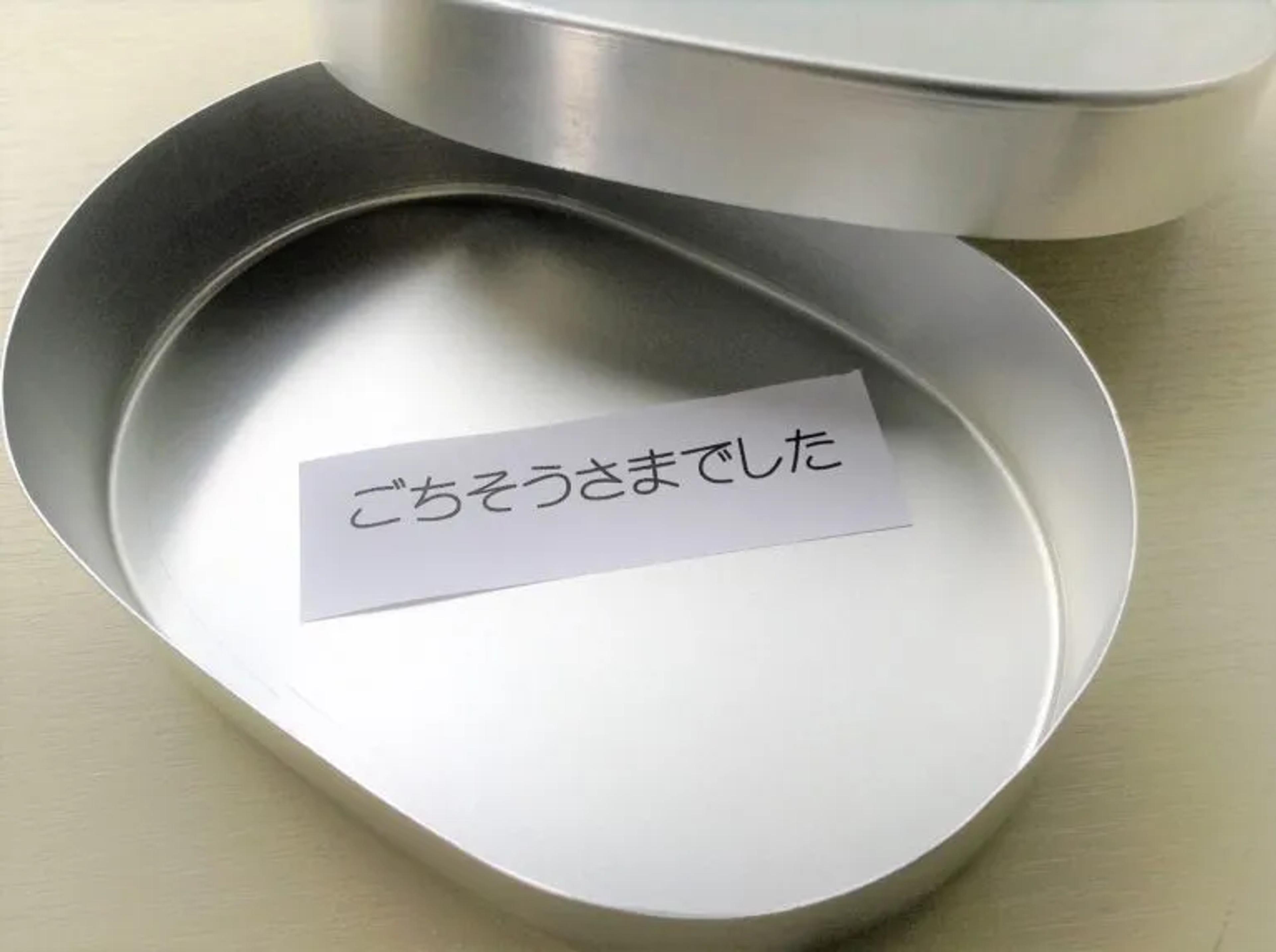 An empty metal lunchbox or bento which has a paper inside which says ごちそうさまでした which is the Japanese word used when you are done eating