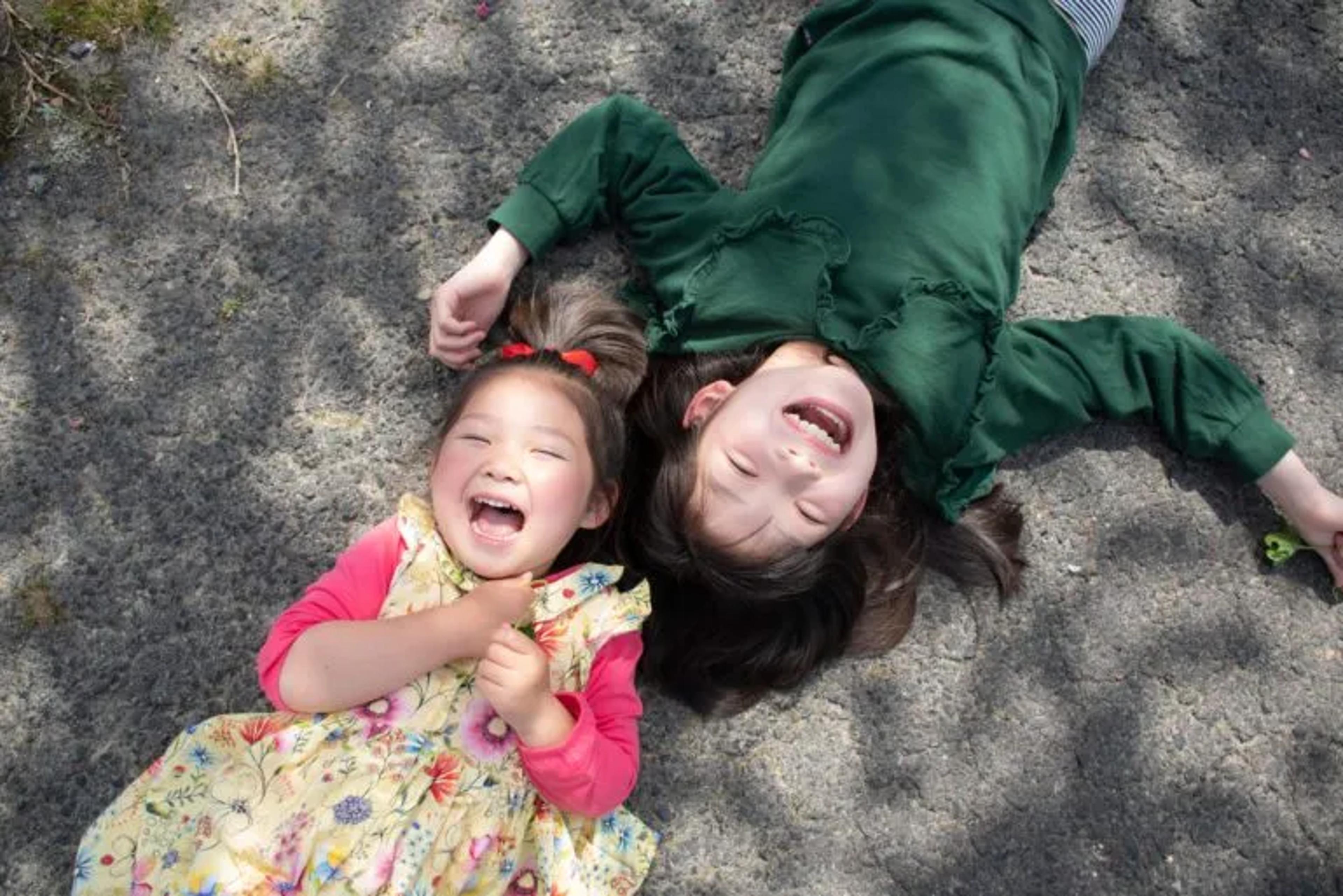 image of two sisters laughing on the ground