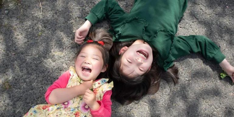 image of two sisters laughing on the ground