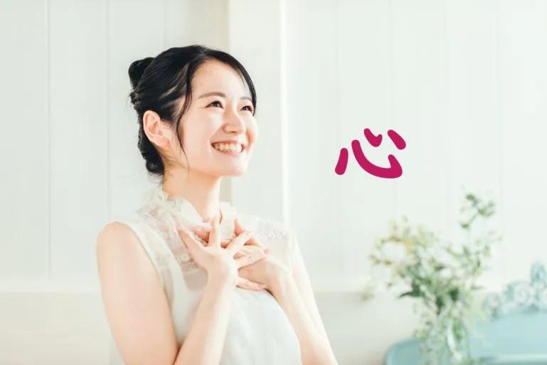 Image of women holder her heart with the Japanese word 心 meaning heart or mind