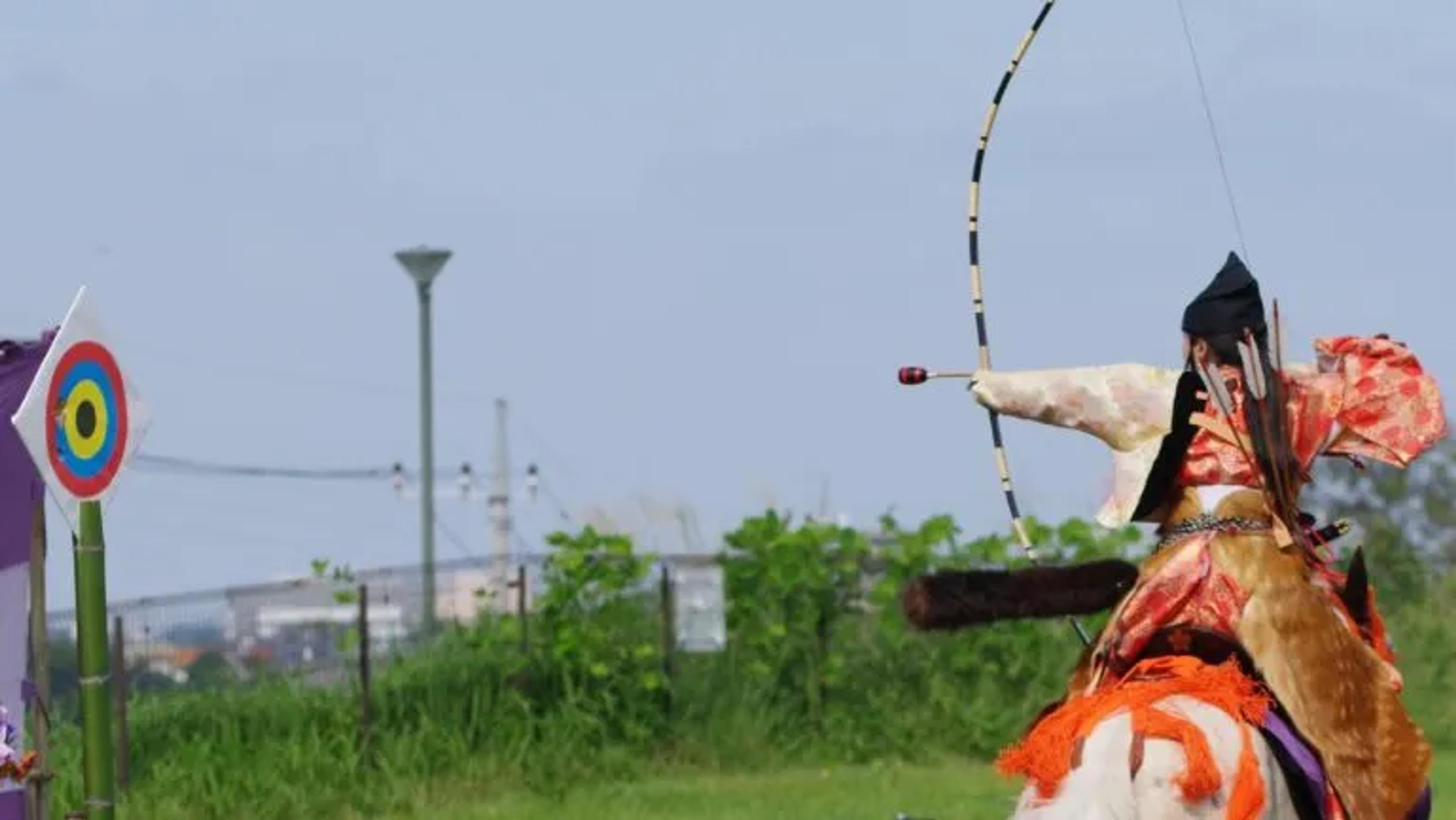 man on a horse with a bow aiming at a target