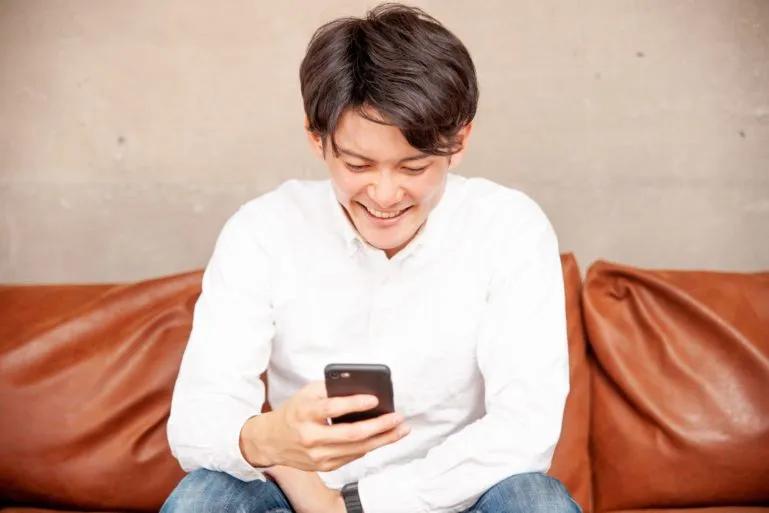 Man smiling while looking at his Smart phone